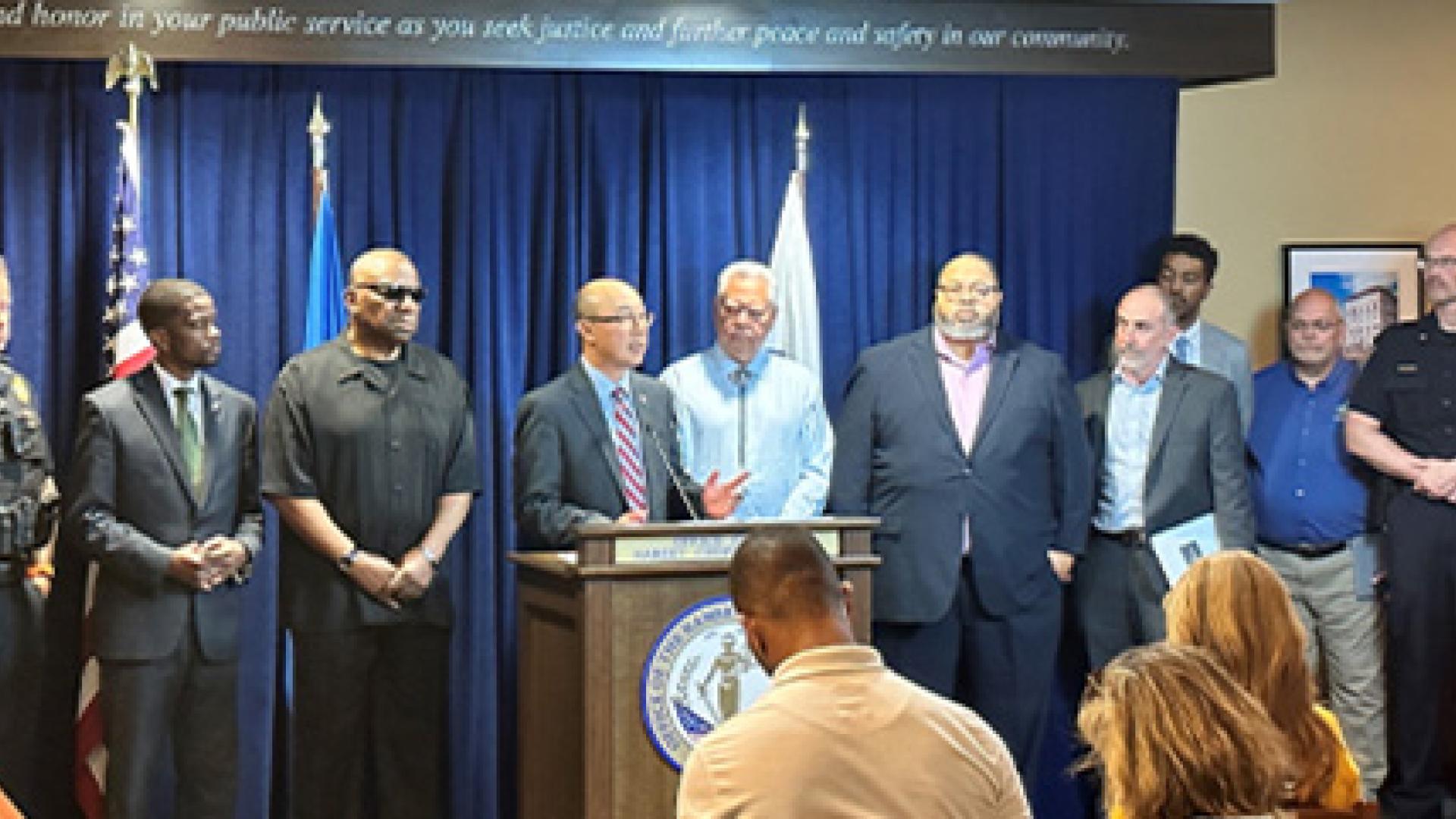 Officials gathered at a press conference with a speaker at the podium