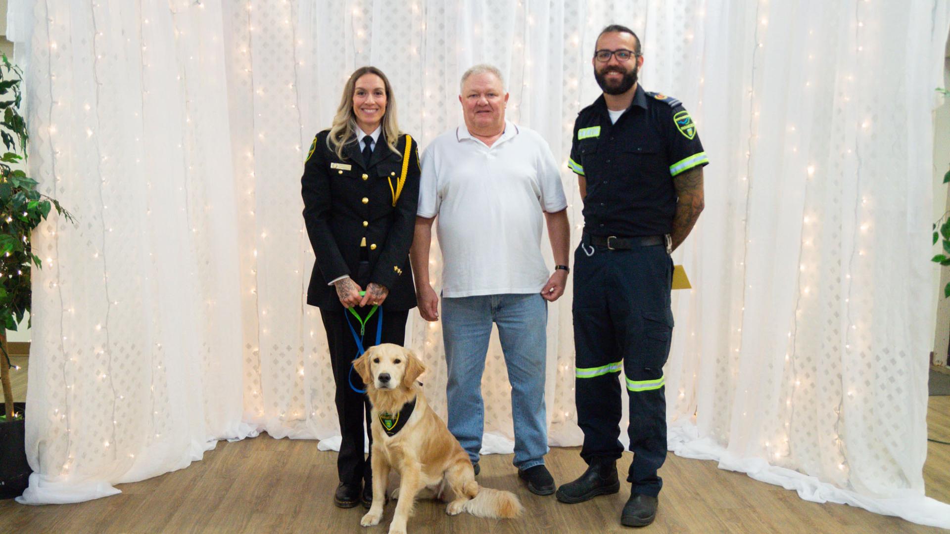 White man in line with two uniformed officers and a golden lab