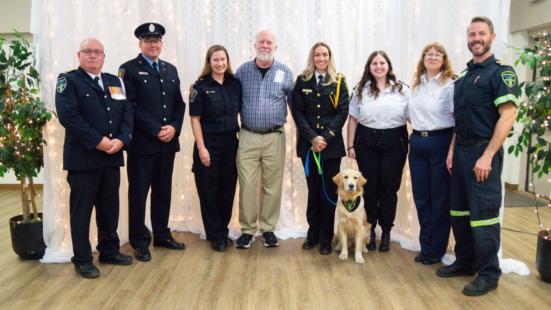 White man in line with seven white men and women in uniform and a golden lab