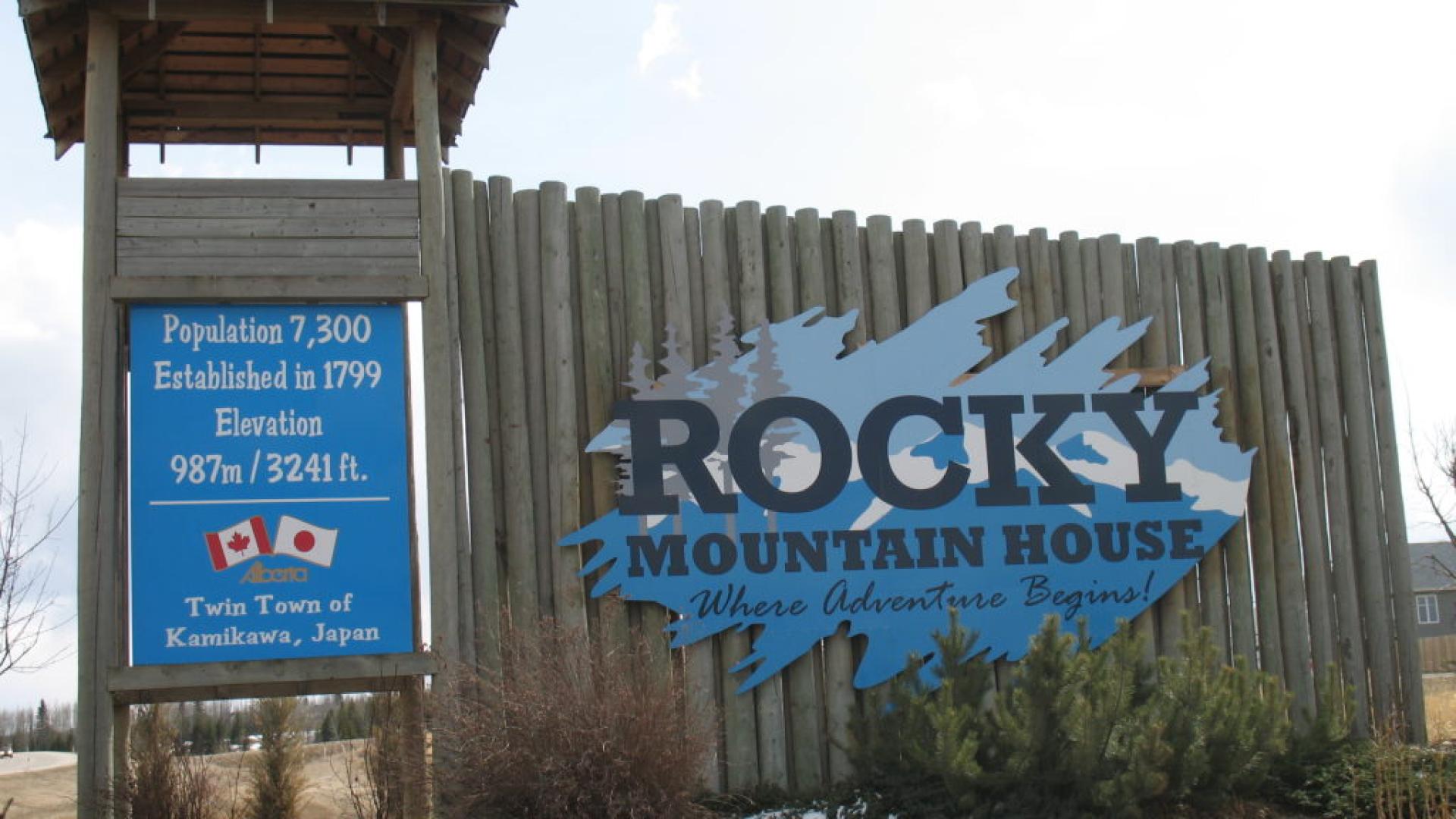 Rocky Mountain House welcome sign with population details and flags.