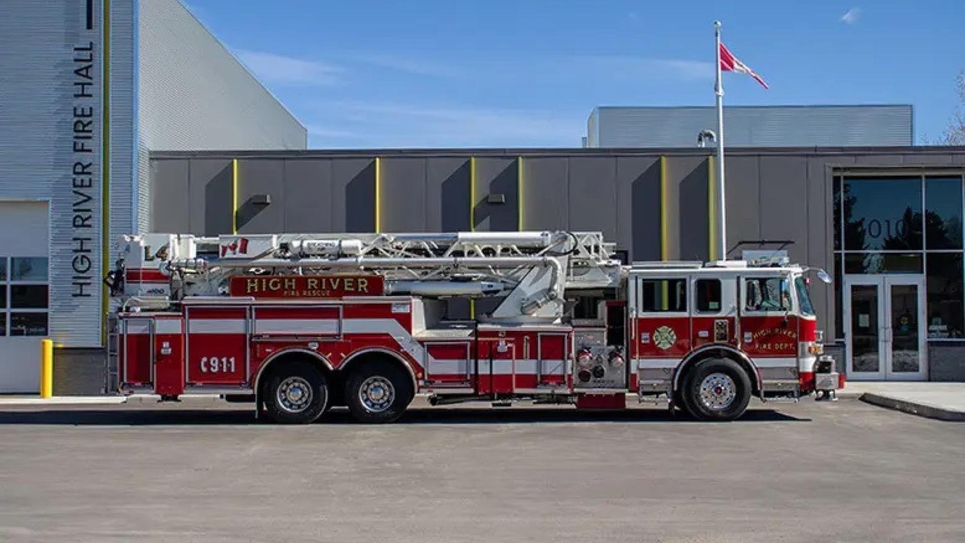 Red fire truck parked outside a modern fire station.